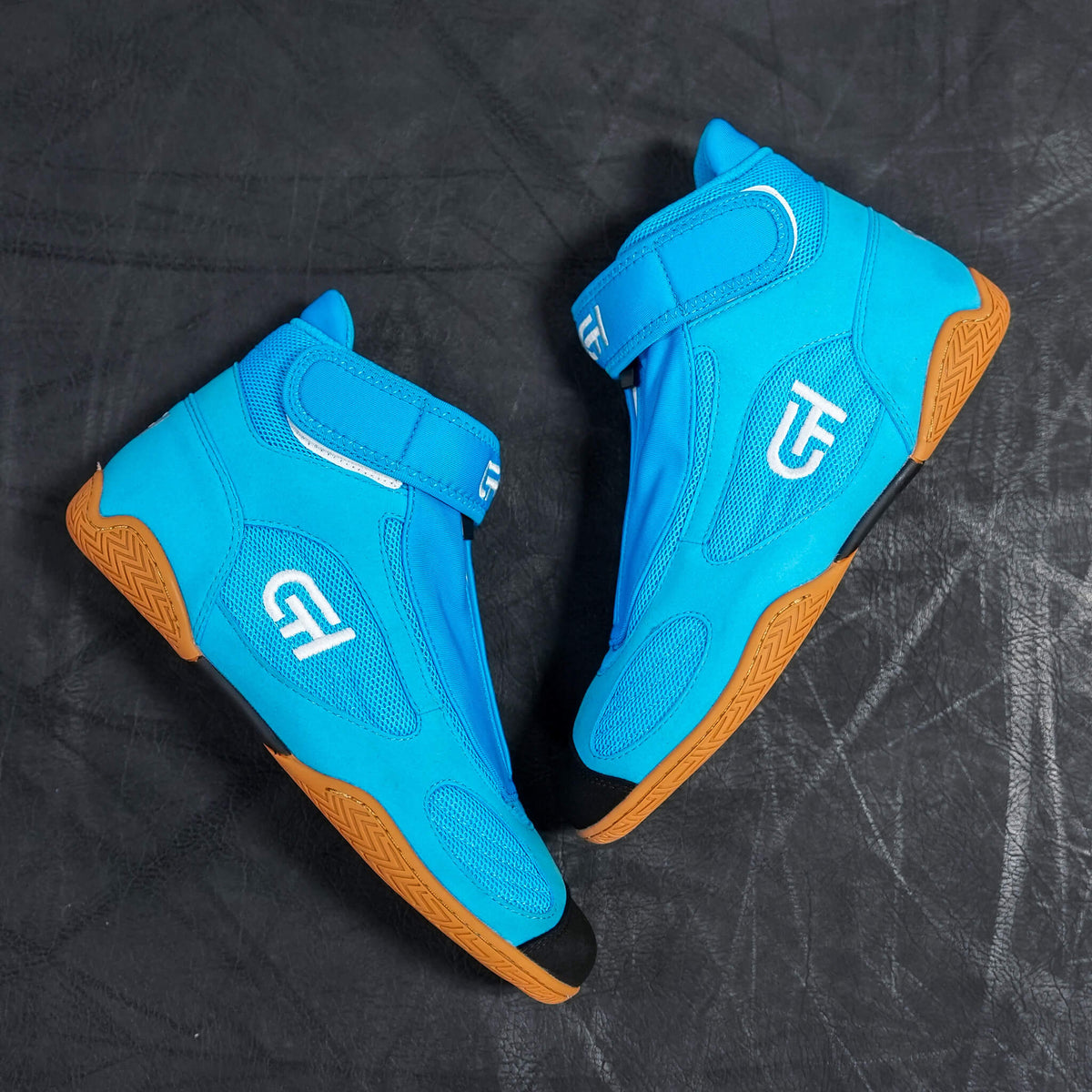 A pair of bright blue high-top CH Gear XXVI Aqua Shoes with white logo graphics and textured brown outsoles, displayed on a dark textured background.