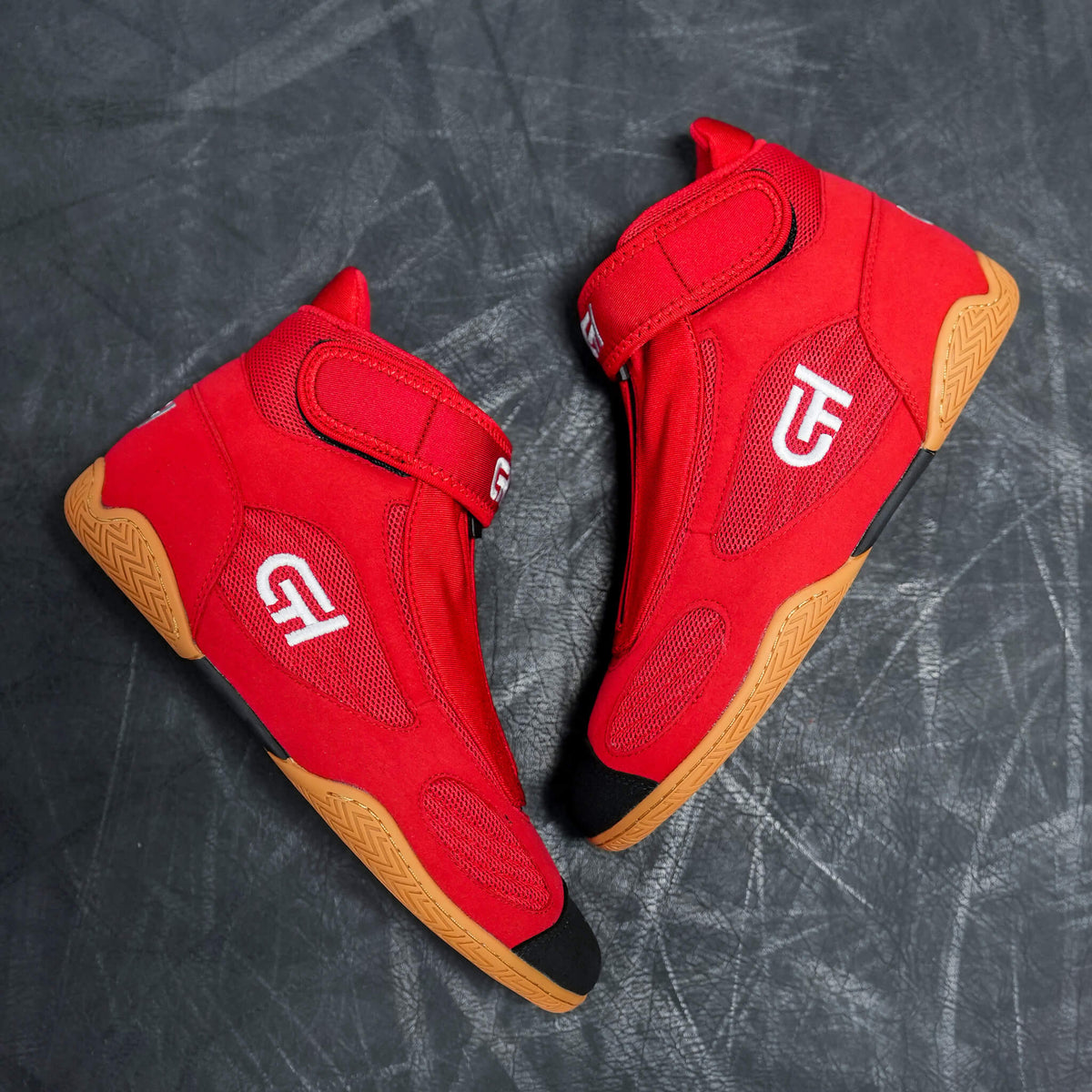 A pair of red high-top athletic CH Gear XXVI Bloodline Shoes with white logo graphics and gum-colored soles, displayed on a dark textured surface.