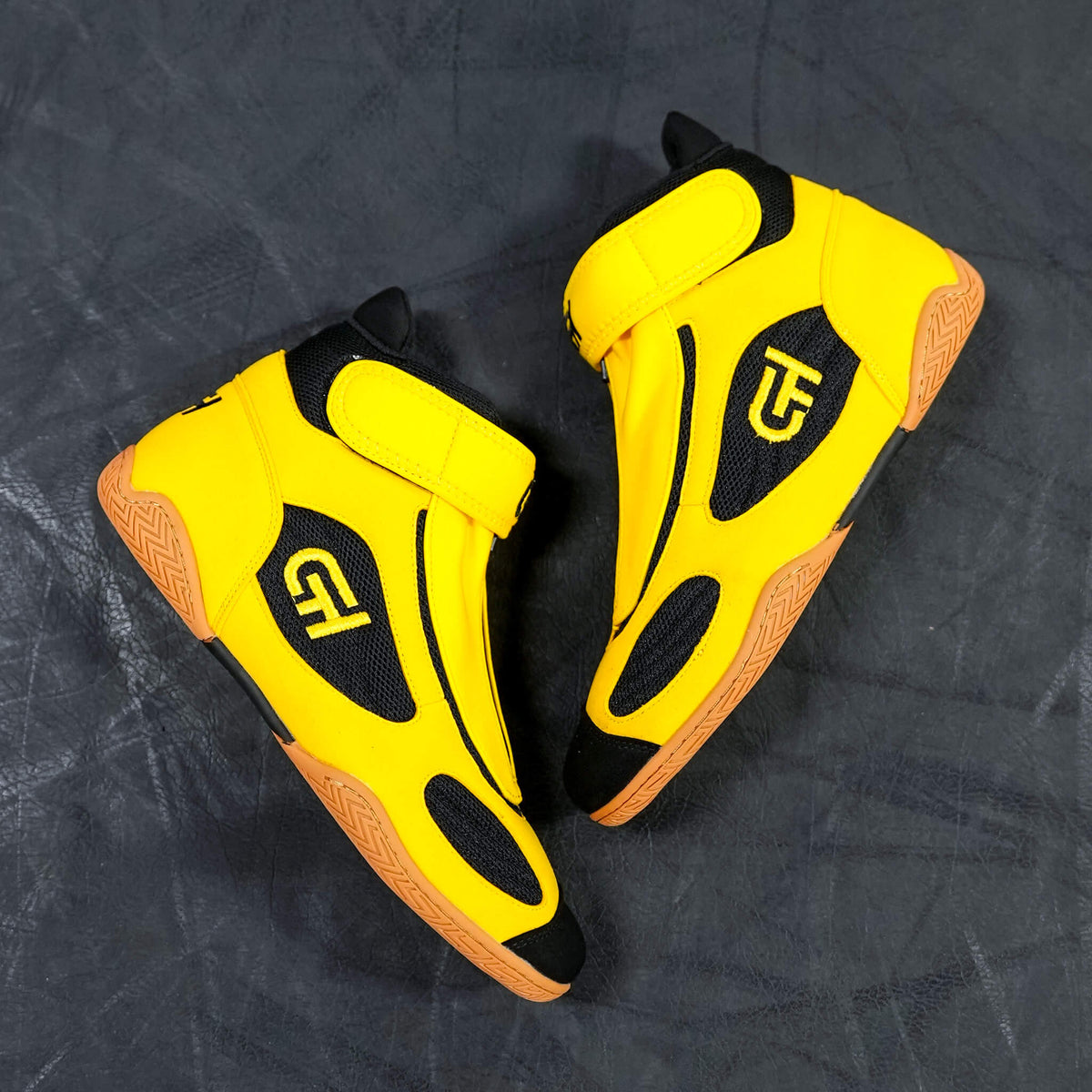 A pair of high-top CH Gear XXVI Bumblebee Shoes in bright yellow and black with orange soles, displayed on a dark textured background.