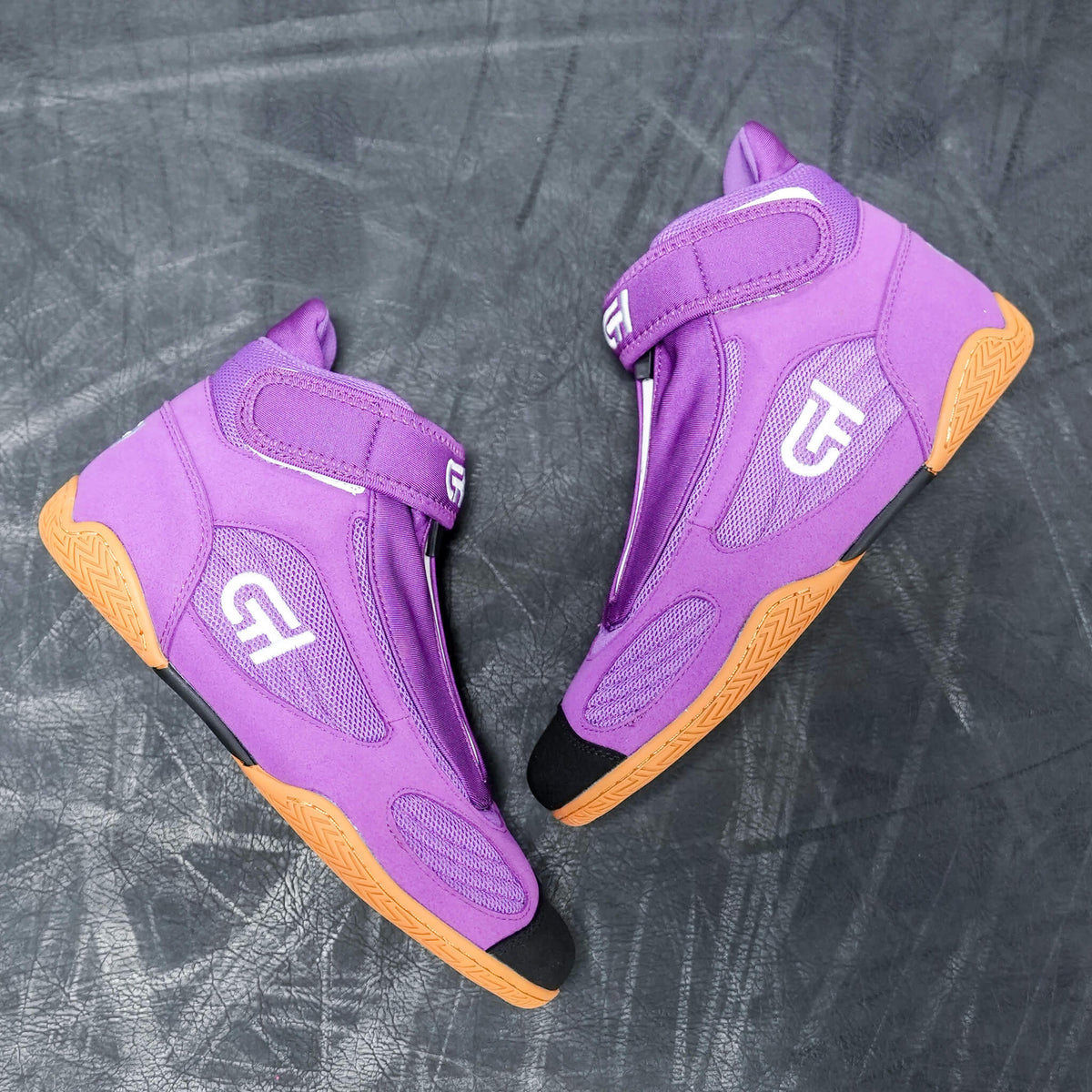 A pair of purple high-top CH Gear XXVI Grape Shoes with orange soles, black toe caps, and white logo details, displayed on a dark textured surface.