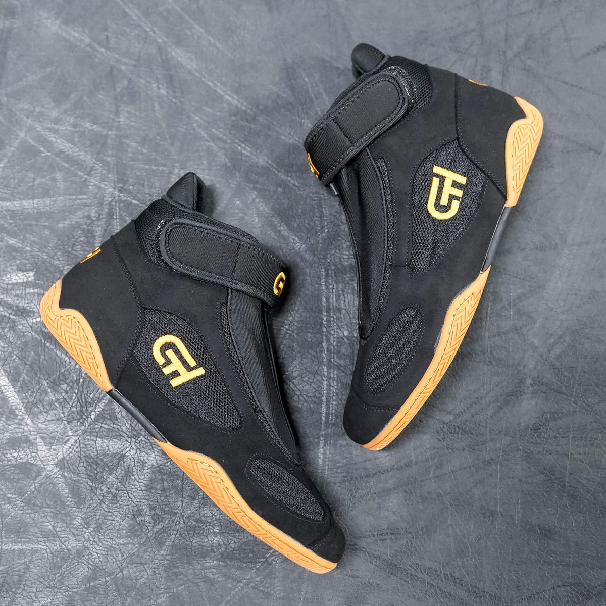 A pair of black high-top CH Gear XXVI Throne Shoes with tan soles and yellow 'CH' logo graphics on the sides, displayed on a textured gray background.